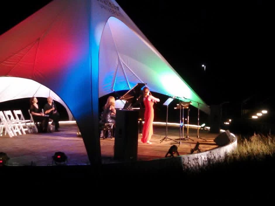 Outdoor evening recital under a lit performance canopy