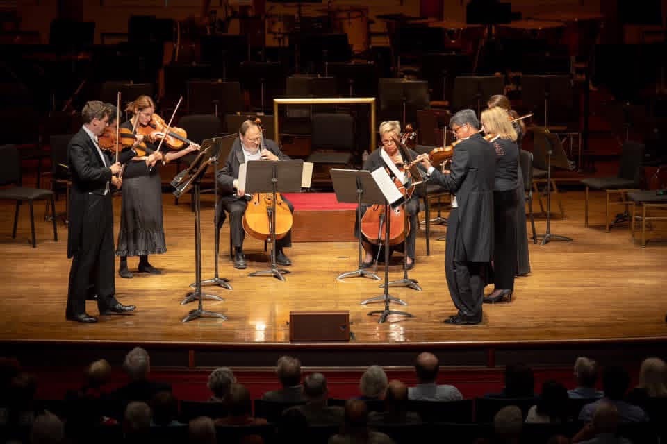 Chamber ensemble performing on stage before a full house